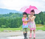 楽しそうに１つの傘に入る二人の子供