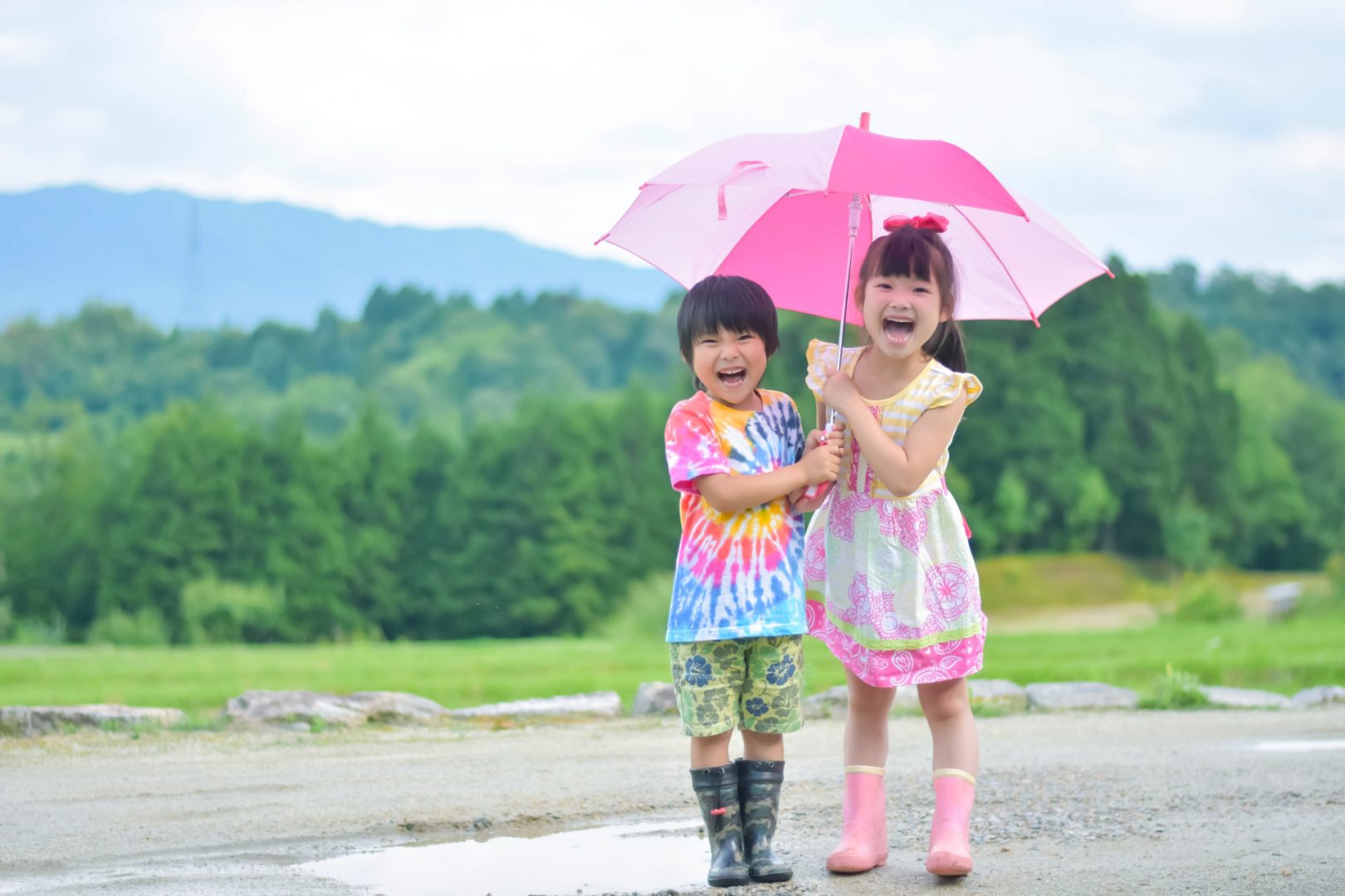 楽しそうに１つの傘に入る二人の子供