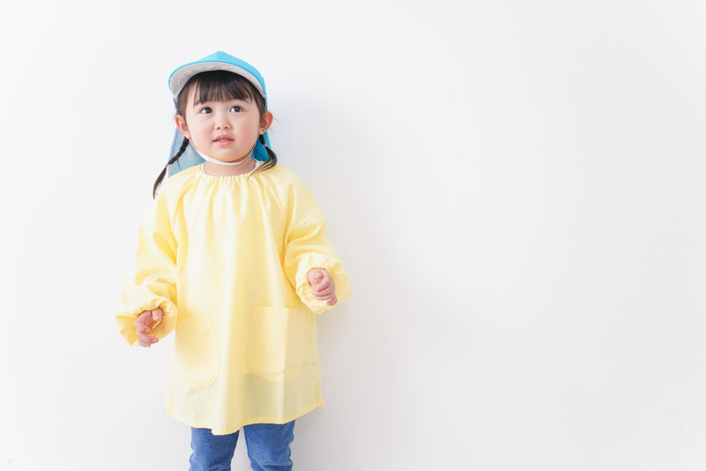 青い保育園帽子と薄い黄色のスモックを着た女の子