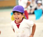 保育園帽子をかぶって運動会で演技をする保育園児